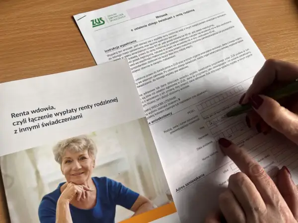 Dłoń wypełnia formularz ZUS, obok uśmiechnięta starsza kobieta.